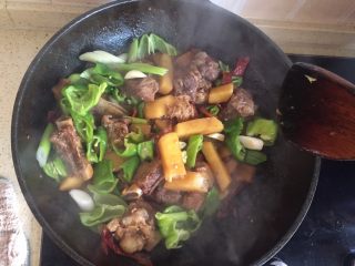 8、土豆烧排骨,汤汁变少后    加入青辣椒和大蒜    继续翻炒   尝一下咸淡    根据口味  加入适量调味料
