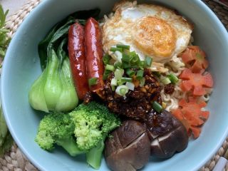 12、烤肠鸡蛋麻辣牛骨汤面,放入烤肠和鸡蛋在方便面表面，浇上麻了调料，撒上葱花。