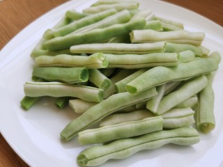 3、干煸芸豆,用手掰成长一点的段。为防止一会炸的时候溅油，可以用厨房纸擦干芸豆上面的水分。