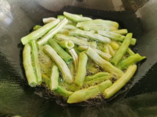 7、干煸芸豆,锅里放入多一点的油，放入芸豆段炸熟。
