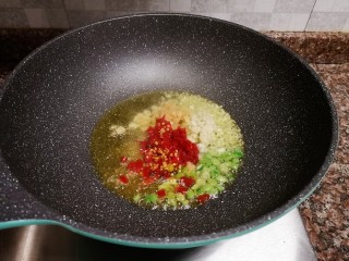 7、剁椒鲫鱼,放入泡姜、泡椒、小葱和大蒜颗粒翻炒出香味。