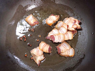 9、干锅千叶豆腐,锅中倒入油，煸香花椒粒，放入腊肉煸出肥油。