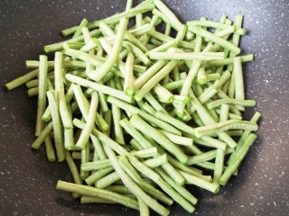 6、干煸豇豆,炒锅内倒多一些食用油烧热,下入豇豆。
