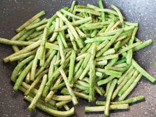 8、干煸豇豆,转中小火不停的翻炒,直至豇豆表面变的皱皱巴巴,盛出备用。