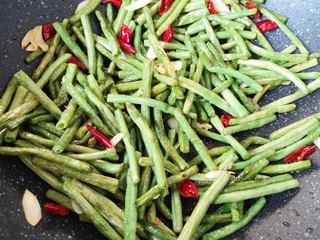 13、干煸豇豆,加入一勺生抽翻炒均匀。