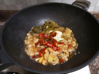 8、酸菜油豆腐烧肥肠,放入酸菜、大蒜、泡椒和泡姜翻炒片刻。