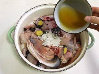 3、香辣水煮鱼,往鱼片中加入腌鱼料包,加入姜片和料酒,用手抓匀,腌制10分钟左右。
