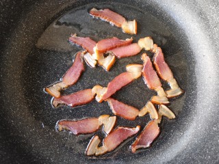 8、干锅茶树菇,另取一锅，加入适量的油烧热后下腊肉片，炒至肥肉部分变得透明。