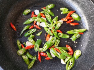 10、干锅茶树菇,接着下入蒜片，二荆条和小米辣翻炒断生。