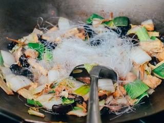 5、罗汉斋粉丝,打开锅，把火调高。加入蒜苗、粉丝。继续翻炒，收汁。