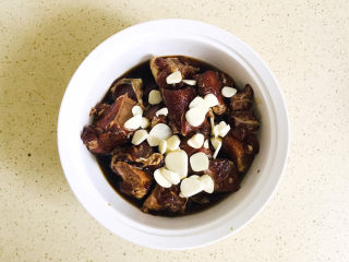 17、剁椒蒸排骨,再将腌制排骨的调料倒进去，大蒜切薄片，平铺在排骨上