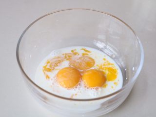 3、玉米面蒸糕,蛋黄里加入牛奶搅打均匀;