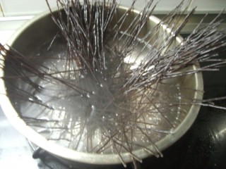 5、黯然酸辣蕨根粉,4.将锅中的水烧开，用手握住蕨根粉的一端，轻轻散开，立即用筷子搅拌，使蕨根粉全部被水浸泡住。将火调成中火，煮约4分钟，直到蕨根粉变软，用筷子掐断，中间没有硬芯