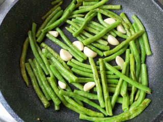 11、豆角烧茄子（少油健康版）,锅中留一点底油，继续将豆角和蒜下锅煸炒。（豆角同样要沥干水份）