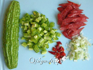 2、地方菜　腊肠苦瓜炒米饭,把苦瓜去瓤切丁；香肠斜切成片；辣椒切粒；葱切碎姜切片。