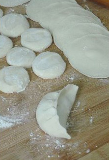 8、徐州过年头牌美食—猪肉饺子,把饺子皮托起，卡在手的虎口处让它自然形成对折，然后将边缘依次折合捏紧，使饺子皮完全粘合即可。