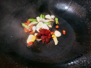 6、水煮千张,热锅烧油，下蒜片，姜片，生辣椒，再倒入一勺豆瓣酱翻炒均匀