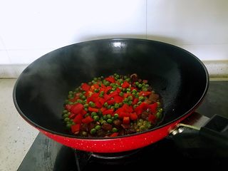 9、小炒腊肉丁,下入洋葱、姜蒜，翻炒约1分钟出香味时倒入豌豆和柿子椒，翻炒2分钟，放盐，炒匀。