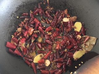 12、独家香辣鸡翅尖,香料炒香后就可以加入干辣椒，一样的翻炒。这里的干辣椒都是我事先剪好的辣椒段，这样处理以后辣椒会更加出味，剪出来的辣椒籽不要浪费，可以都放进锅里一起炒