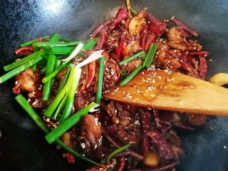 21、椒香辣子鸡,撒上白芝麻，倒入葱段，翻炒均匀，停火起锅