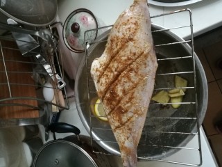 2、柠香烤马面鱼,经过一晚腌制拿出来后撒五香粉，孜然粉，孜然粒，用油刷涂抹均匀，油和调料充分混合涂遍鱼身