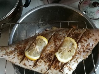 4、柠香烤马面鱼,柠檬片切薄点，能使两端镶嵌在刀口中，翻面，这样柠檬既不会从烤架掉下来也更入味