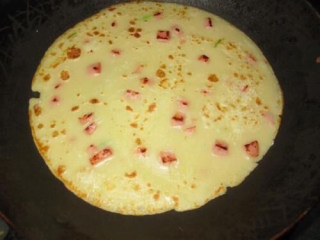 11、快手早餐—火腿蛋饼,将拌好的蛋饼糊倒入锅中摊平。