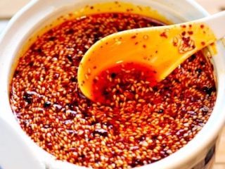 6、秘制陕西正宗凉皮专用辣椒油（绝密秘方）,泼油浸渍辣椒面：将精心炼制的香油高温 倒入拌过调料的辣椒面，一边倒入一边不停的用筷子搅拌均匀。待油全部倒入辣椒面里后，立即加入 镇江香醋 20g ，然后撒上 炒熟的 白芝麻 80g  ，同样搅拌均匀，盖上盖子密封，静置一晚（12-24 小时都可）。 练好的辣椒油不宜立即使用，因为香味不醇厚，还未充分散发出，最好加入陶罐或有盖的容器，加盖自然冷却浸渍 12 到 到 24 小时，这样就做好了，因为加入了紫草，成品效果油色明亮，色泽金红，香味醇浓，辣味突出。