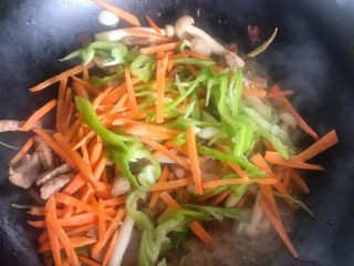 16、白玉菇炒肉,再倒入胡萝卜丝和青椒丝继续翻炒均匀