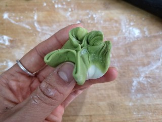 19、八宝百财蒸饺,把五星每一边用右手拇指指肚向中心推，形成菜叶状纹理，然后压至五星的下一边，依次完成。