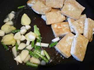 7、菌茹烩豆腐,把豆腐推到一边,倒入葱姜蒜等调料。