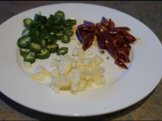 1、酸菜肥牛,将青辣椒，切片干辣椒切段，蒜切末。