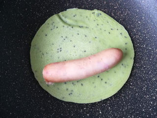 6、金枪鱼肠鸡蛋卷,一面煎至凝固，翻面。卷入一根金枪鱼肠。