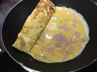 4、「吃货久久」小森日系鸡蛋卷升级版,倒入剩下蛋糊 稍微抬起之前的鸡蛋卷让蛋糊留入铺满锅底