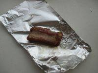 6、微波红酒排骨,取一块锡纸,在亚光面放上一块排骨,仔细包严包好。