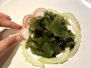 6、初夏,萝卜切片后，对折再切一刀，重叠稍微挫开层次 依次摆入西芹与海木耳中间。