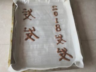 15、“发财”蛋糕卷～2018专属,油纸上提前薄薄涮点油，然后把可可液裱出字体，送入烤箱预烤5分钟定型取出，再倒蛋糊（字体要反面写，这样卷起来才能显示正面，否则按正常写字，反面卷起字就反了）