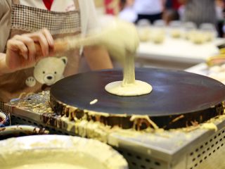 5、天津老味煎饼果子,当煎饼果子铛温热时，盛一汤勺满眼黄绿色的绿豆面糊倒在铛上。