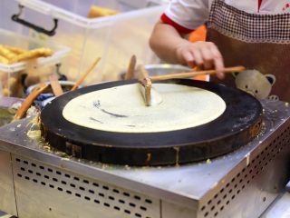 7、天津老味煎饼果子,用“竹蜻蜓”刮子以铛的中心为圆心轻轻划几圈