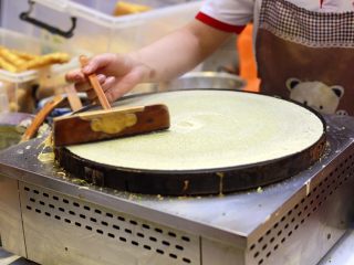 8、天津老味煎饼果子,一直画到铛的边缘，瞬间薄如蝉翼的一张煎饼就摊成了。