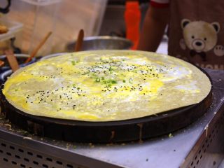 11、天津老味煎饼果子,蛋液被煎得直冒小泡泡，撒上些黑芝麻和翠绿的小香葱。