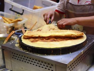 13、天津老味煎饼果子,把一个果蓖儿横着放在煎饼的中间，用前后的煎饼裹上果蓖儿。