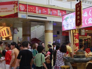 19、天津老味煎饼果子,天津南市食品街的煎饼果子摊一共有四个摊位，东西南北门各有一个摊位，这是游客们买煎饼果子排队的情景。