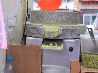 20、天津老味煎饼果子,这是小石磨，居民楼群里摊位大多使用这种小石磨。图中右下方的桶里放的是泡好的绿豆。