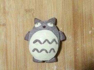 8、龙猫豆沙包,揪适量白发面，压成小圆片，做成龙猫肚子和眼睛，用黑米面团搓小条做肚子上的花纹。做好的这些小装饰和红豆，芝麻都用水贴在龙猫身体上就可以。