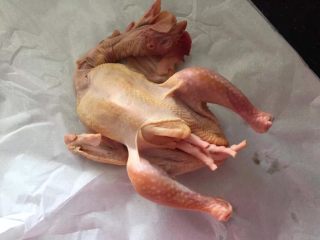 4、砂锅盐焗鸡,腌制好的鸡取出沥干水分(或者用厨房纸巾拭干水分),鸡爪塞进鸡肚子里,用砂纸包好。