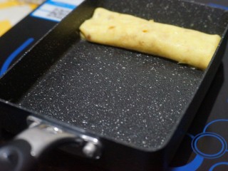 11、芝士肉松玉子烧,将卷好的第一层推到顶端，锅底刷油。