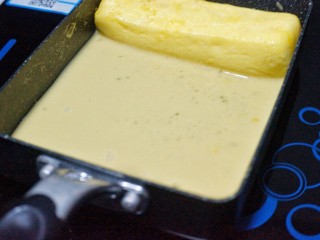 16、芝士肉松玉子烧,将卷好的第二层推到顶端，锅底刷油，倒入最后一层蛋液。