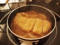4、猪排丼,取一个小锅子(用小锅子刚好一人份,如果人多,可以用大的平底锅,一下子做多份),锅子里面放入柴鱼汤(昆布放水里浸一晚上最好,然后放入柴鱼一起煮开晾凉就可以了)、切条的洋葱,一勺味啉,一勺砂糖,一勺生抽,开火煮,这个时间把炸好的猪排切块,等汤有点煮开的时候把猪排放进去煮一会儿让猪排吸饱汤汁。