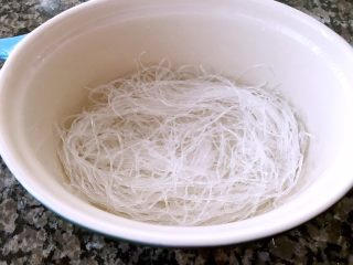 3、海鲜豆腐煲,粉丝用凉水泡半小时,主要作用是为了软化,以及清洗。用手掐一下,能掐断但又不是那么容易掐断的时候,将粉丝捞起来,沥干水分铺在小砂锅底部备用。